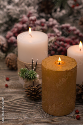 Fir branch in snow, lighted candle, cone on wooden background. Christmas theme