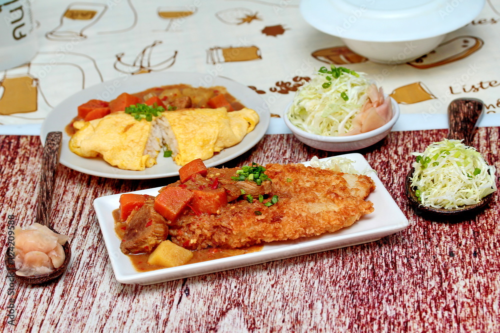 Close up deep fried dolly fish in Japanese style topped yellow curry with sliced cabbage and pickled ginger. Selective focus.