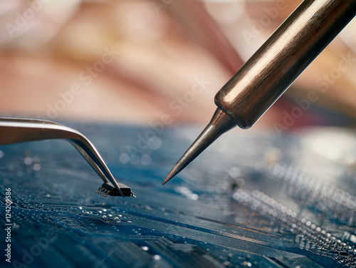 Computer repair concept. Tweezers with chip and soldering Iron
