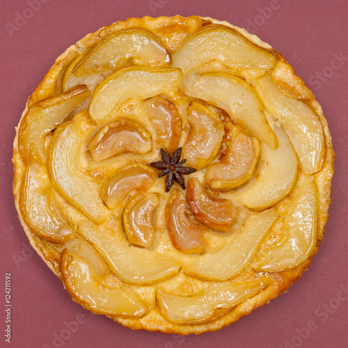 Whole tarte Tatin apple pear tart isolated on claret background