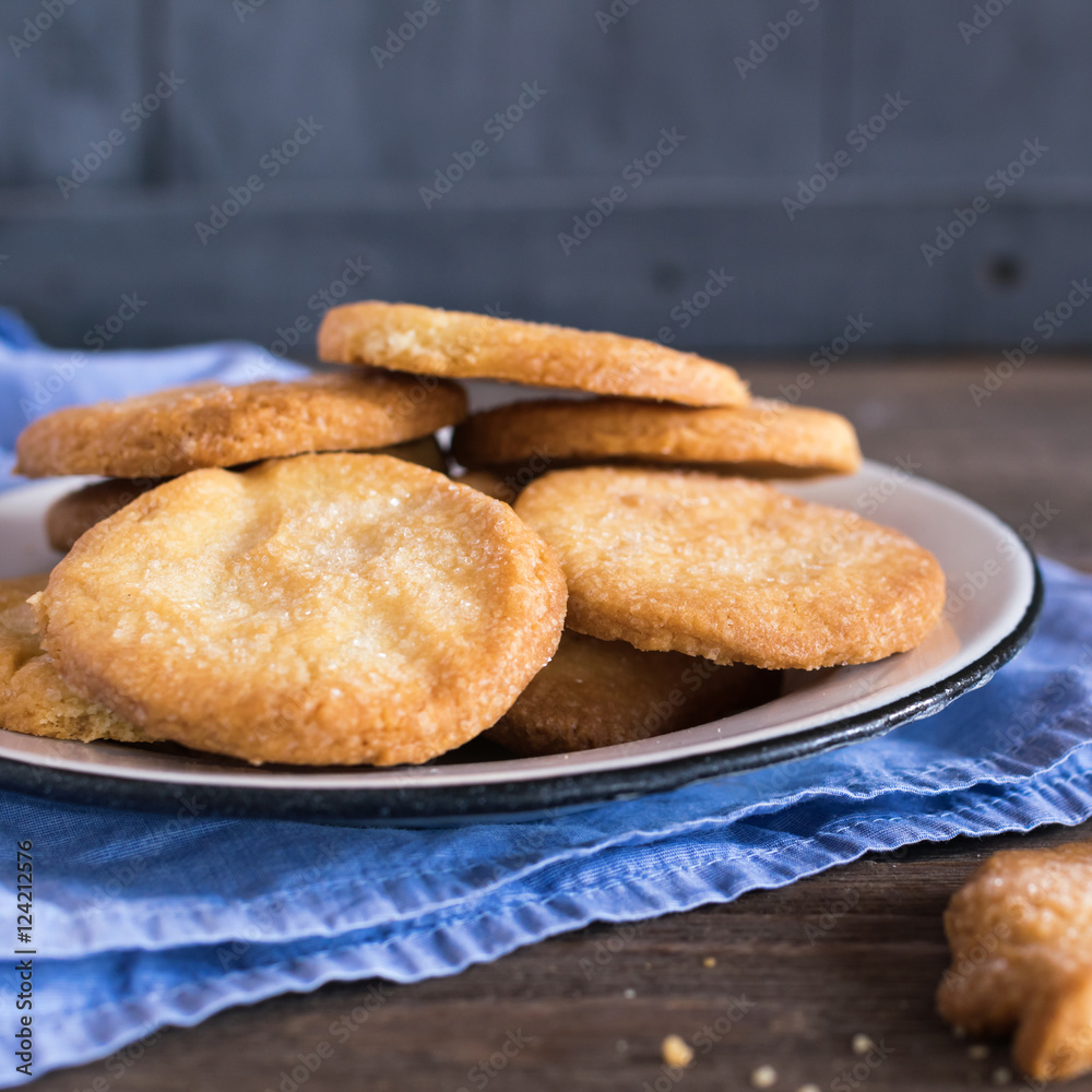 Crispy cookies in white metal bowl on a blue napkin.