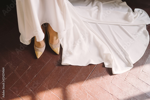 closeup of a bride in white lace wedding dress put on her shoes