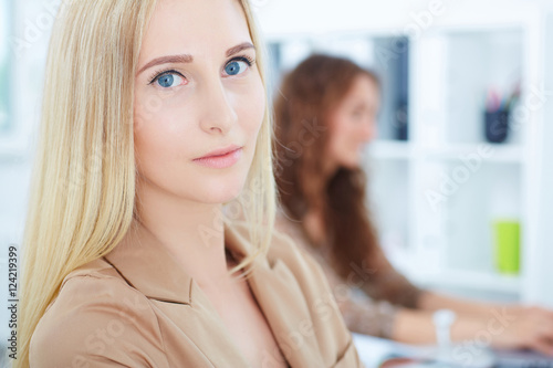 Portrait of young beautiful businesswoman with female colleague on the background.Serious business and partnership, job offer concept.