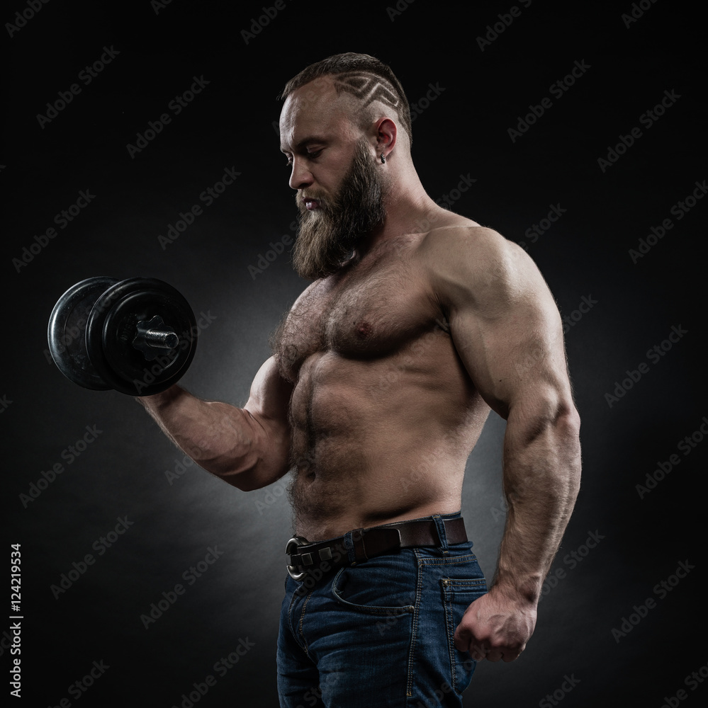 Power athletic bearded man in training pumping up muscles with d