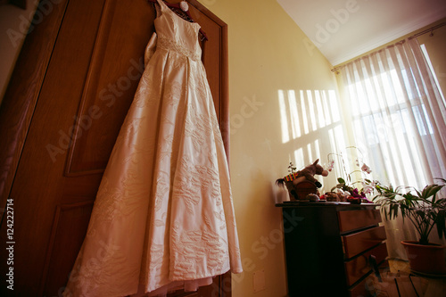 Classy beige dress hangs from the wooden door