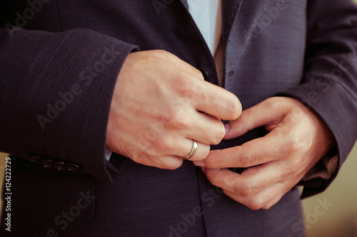 Closeup of married man s hands buttoning up black jacket