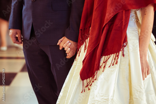 Groom holds a hand of bride dressed in red shawl