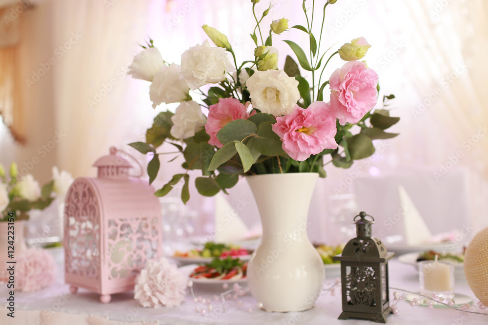 Beautiful pink and delicate vase with flowers standing on the ta