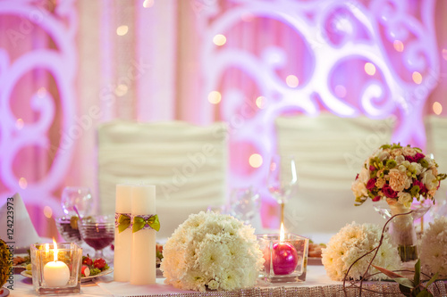 Wedding dinner table decrated with white candles and flowers