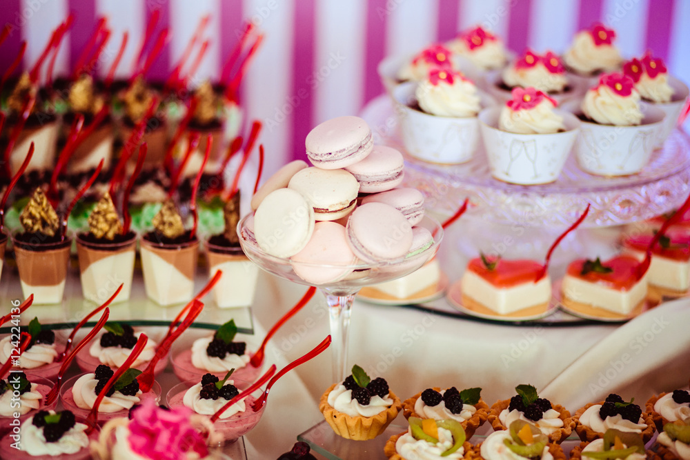 Naklejka premium White macaroons lie on the glass vase among other sweets