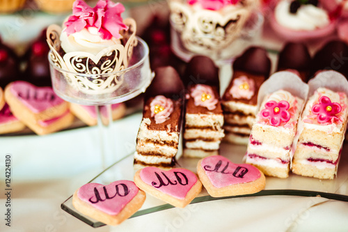 Baked hearts with pink glaze lie behind the cakes