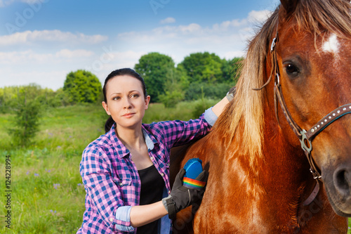 Portrait of young woman brushing beautiful horse