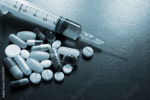Drugs and syringe on wooden table with room for text, medical concept.