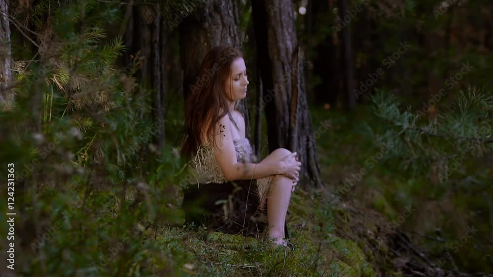 Attractive young woman sitting in the forest alone Attractive young woman sitting in the forest alone