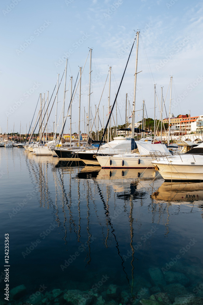 Boats and ships at pier in Rovinj, Croatia at sunset. Masts are reflected in the sea