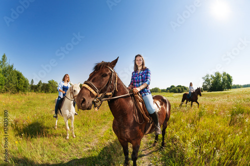 Three female equestrians riding horses in field