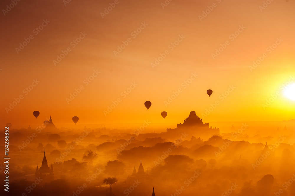 Amazing misty sunrise colors and balloons silhouettes over ancient Dhammayan Gyi Pagoda. Architecture of old Buddhist Temples at Bagan Kingdom. Myanmar (Burma). Travel landscapes and destinations