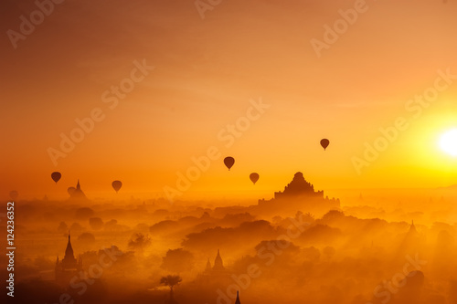 Amazing misty sunrise colors and balloons silhouettes over ancient Dhammayan Gyi Pagoda. Architecture of old Buddhist Temples at Bagan Kingdom. Myanmar (Burma). Travel landscapes and destinations photo