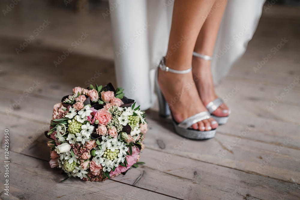female feet in white wedding sandals with a bridal bouquet female feet in white wedding sandals with a bridal bouquet