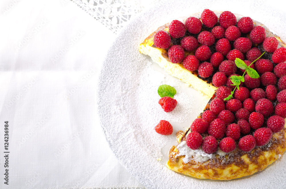 Cheesecake, souffle, cream mousse, pudding dessert with fresh raspberries and mint leaves on a white plate Cheesecake, souffle, cream mousse, pudding dessert with fresh raspberries and mint leaves on a white plate