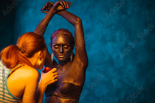 Model closes her eyes while artist covers her body with bronze p