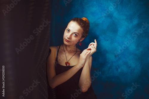 Model crosses her hands while standing thoughtful at blue wall