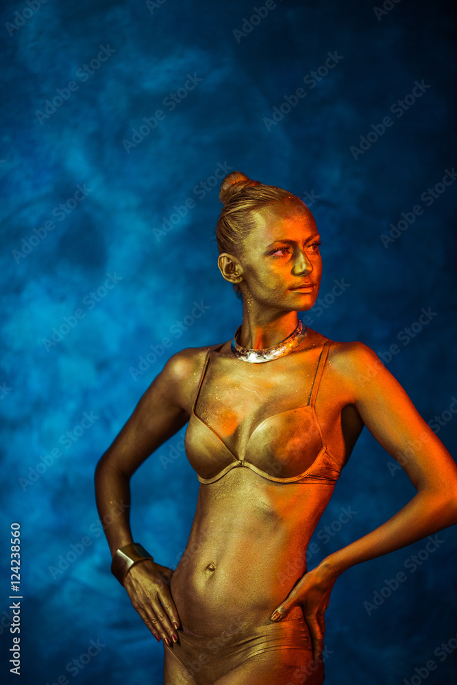 Golden model holds her elegant arms on her waist