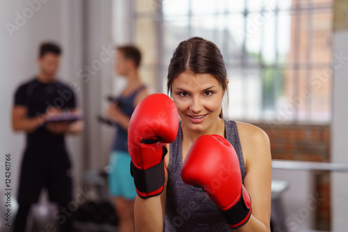 lächelnde frau trainiert mit boxhandschuhen im fitnesstudio photo