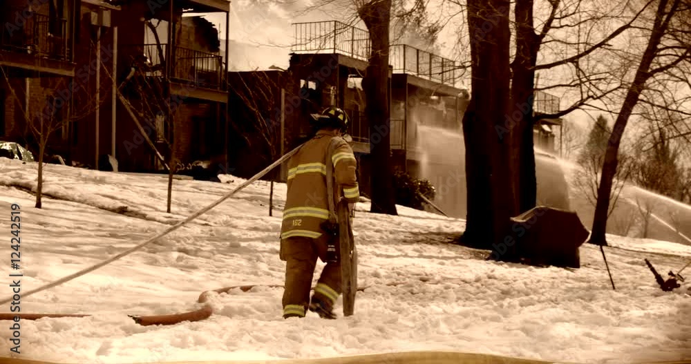 Firefighter walking with firehose to a nearby house Firefighter walking with firehose to a nearby house