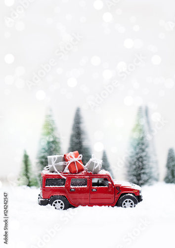 Snowy Winter Forest with miniature red car carrying christmas presents