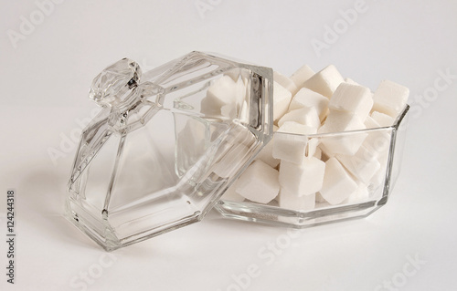 Fotografía Lump sugar. Glass sugar bowl with lid on white background