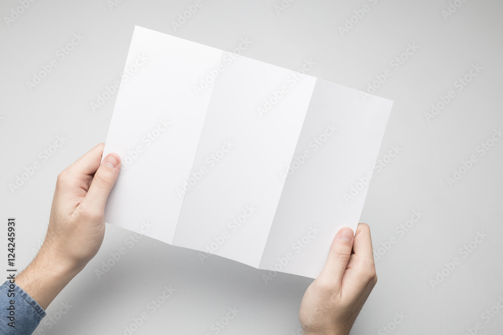 Hands are holding a Dl Tri-Fold white paper Flyer