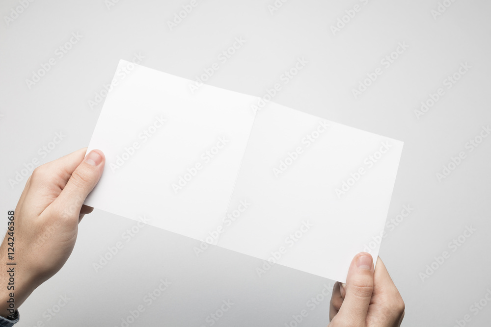 Man in blue shirt is holding a square Bi-Fold white paper flyer Man in blue shirt is holding a square Bi-Fold white paper flyer