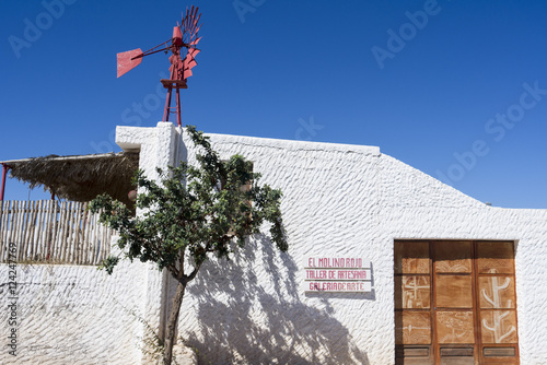 Red windmill for water supply on a roof top of a white mediterra photo