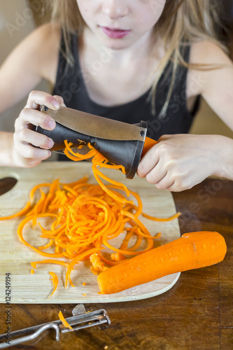 Girl using spiral vegetable slicer, partial view photo