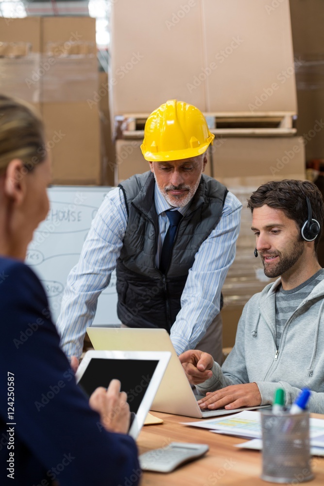Warehouse manager and staff discussing with laptop Warehouse manager and staff discussing with laptop