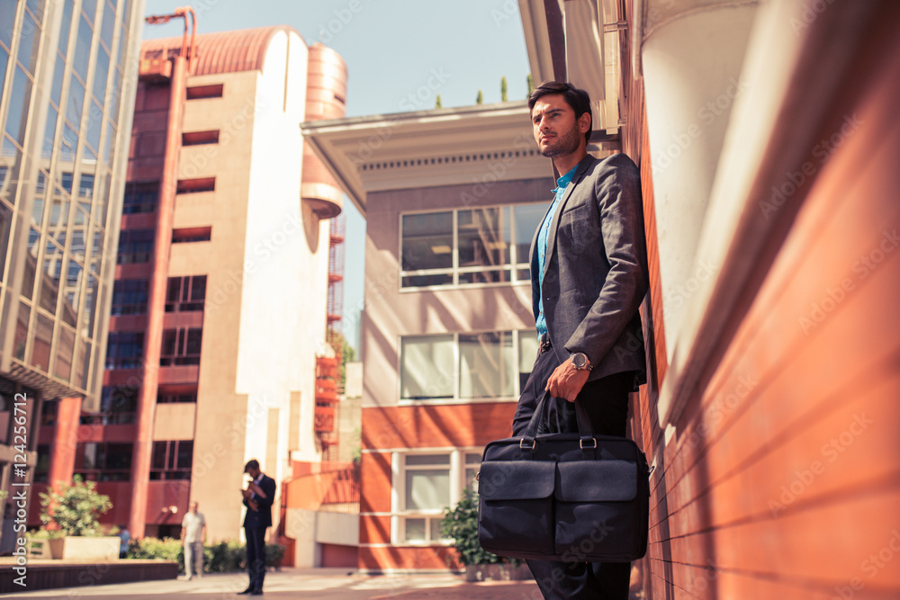 Young businessman in suit with briefcase in the street Young businessman in suit with briefcase in the street