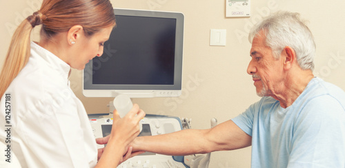 Female doctor with male patient undergoing arm echography