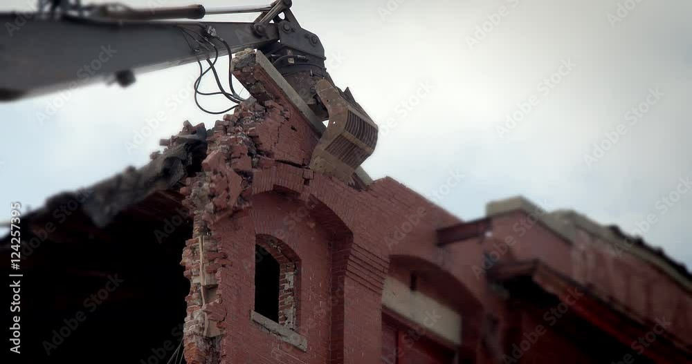 Excavator destroying brick building