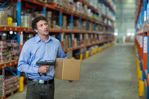 Warehouse worker holding cardboard box 