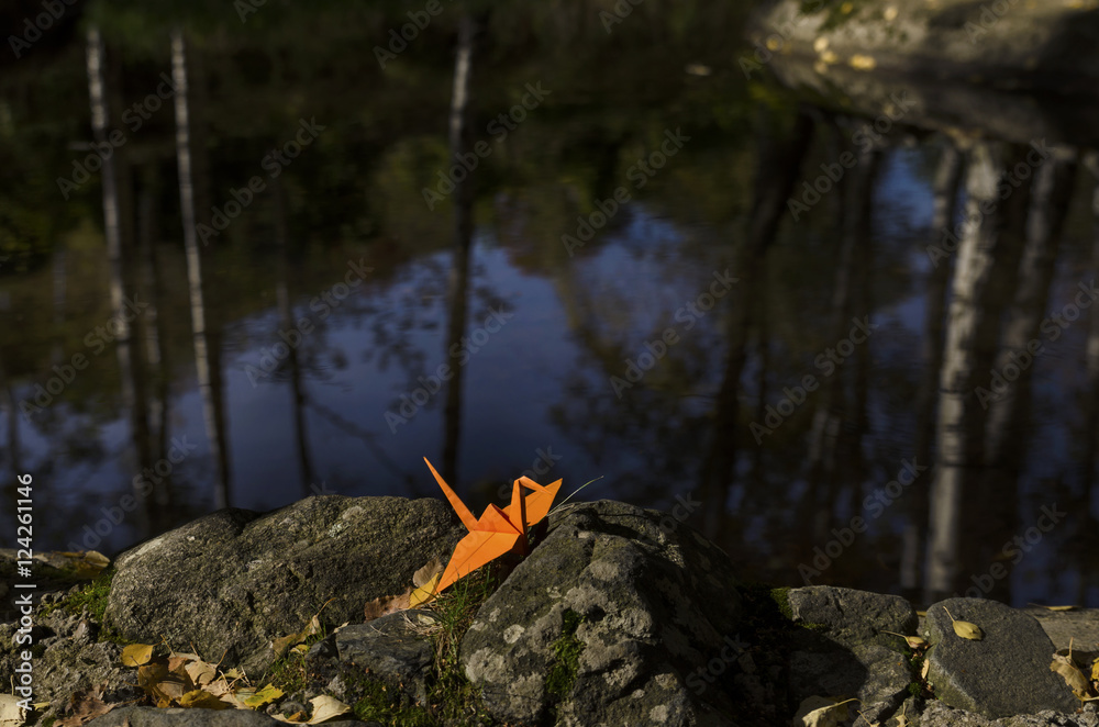 Orange origami crane and water reflections Orange origami crane and water reflections