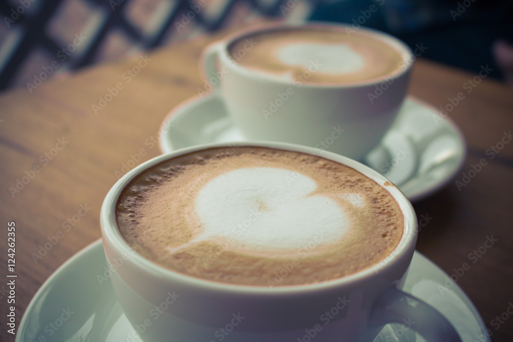 Obraz premium Top view two coffee cup latte art on wood table vintage tone.