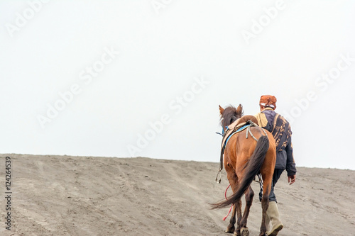Mt. Bromo , East Java, Indonesia. May 21, 2016. A horseman walking his horse on sand dune after providing horseback riding services to tourist at Bromo-Tengger-Semeru National Park, a nature reserve.