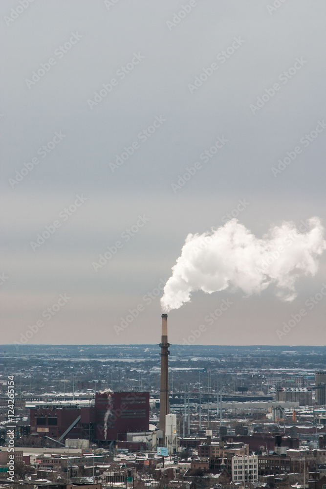Smoke stack from power plant spewing pollution in busy city