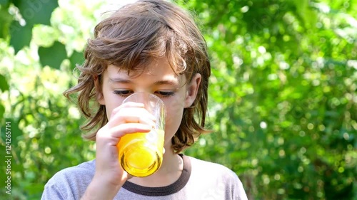 Boy is drinking orange juice outside