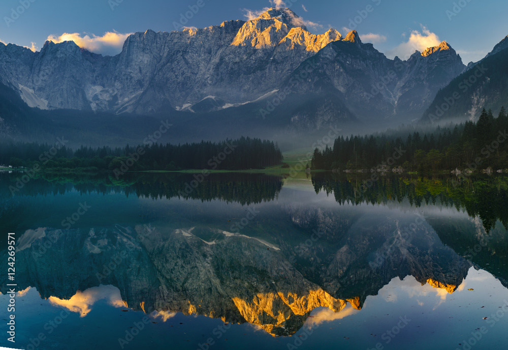 Alpy Julijskie odbijające się w tafli jeziora o poranku