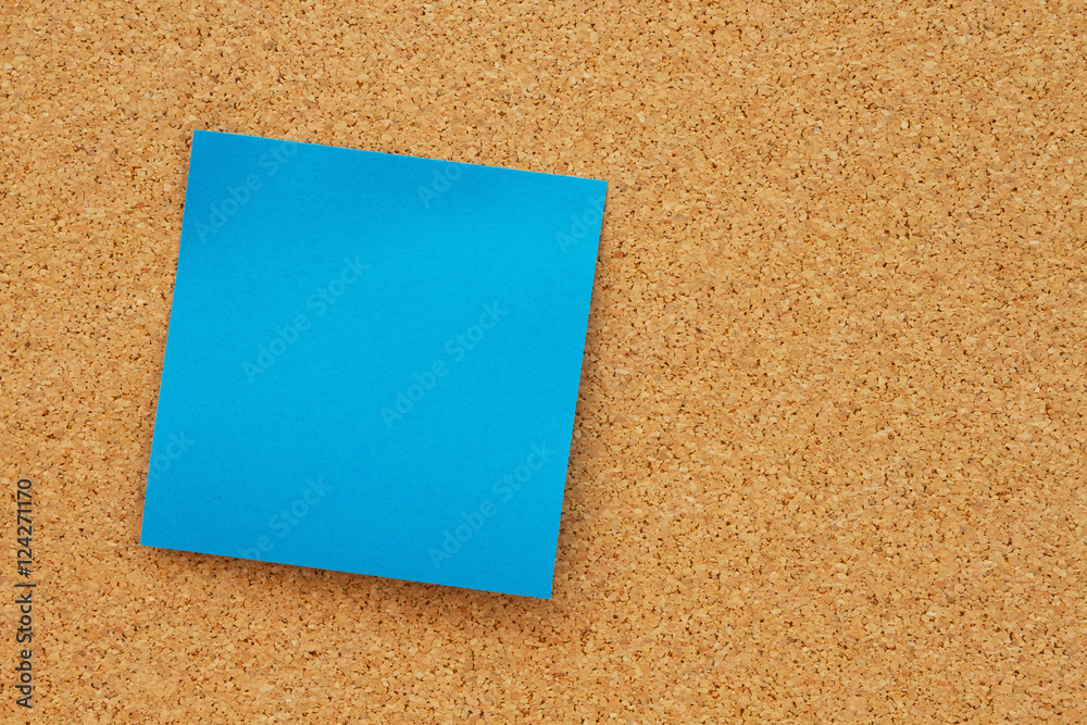Bulletin board with a blank blue sticky note Bulletin board with a blank blue sticky note