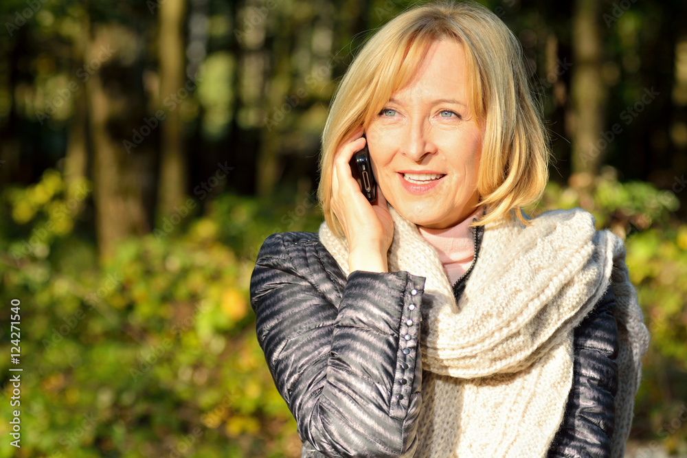 Attraktive Seniorin telefoniert mit Smartphone im Wald Attraktive Seniorin telefoniert mit Smartphone im Wald