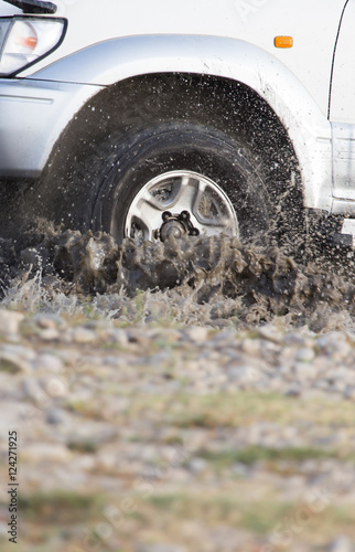 Car wheel in a spray of dirt and water
