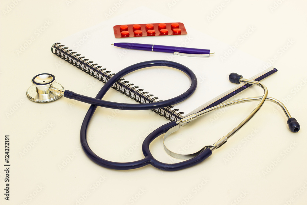 A stethoscope, notebook, pen and pils on a white background A stethoscope, notebook, pen and pils on a white background